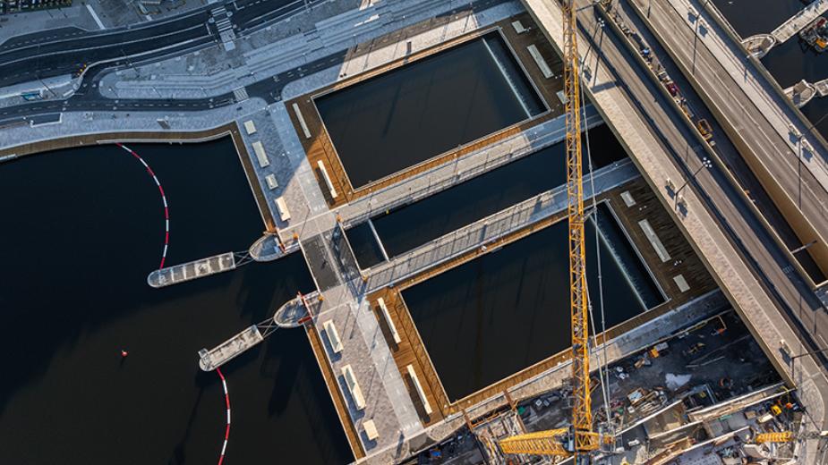 Bild tagen rakt uppifrån över Slussens nya slusskanaler och avbördningsluckor i Stockholm, med en lyftkran i förgrunden.